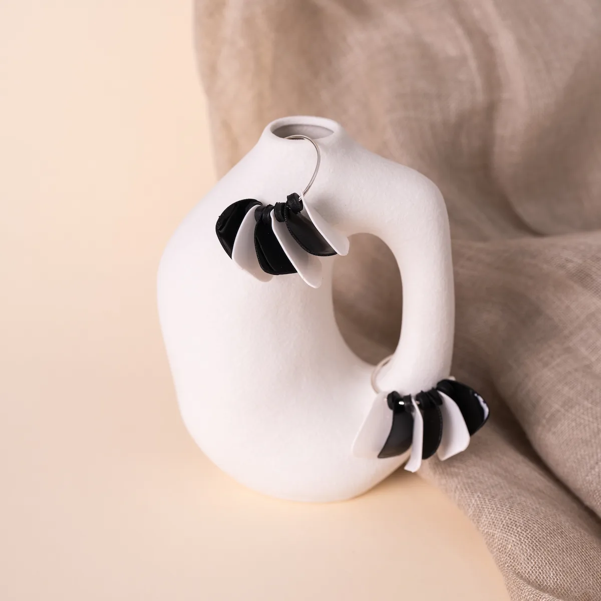 Pendientes artesanales Aire de cebra, en plata de ley 925 y arcilla polimérica. Foto en modelo. Un aro de plata con pétalos en tonos negros y blancos. Ligeros y exclusivos.