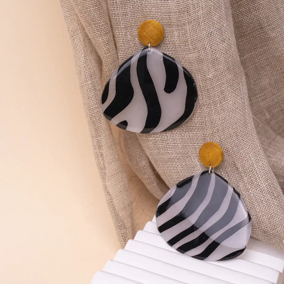 Pendientes artesanales Cebreando en plata de ley 925 y arcilla polimérica. Foto en modelo. Un cabujón de madera de haya pegado al lóbulo con una pieza estampada de cebra, resinados para que brillen. Ligeros y exclusivos.