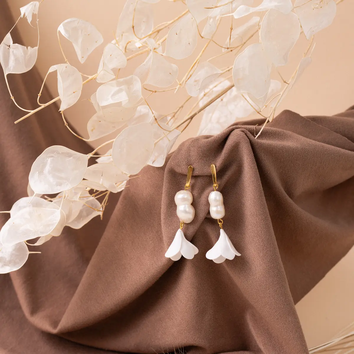 Pendientes artesanales Flor Lis blanca, de plata de ley 925 bañada en oro y arcilla polimérica. Un delicado enganche de plata bañada en oro de 24 quilates en la que cuelgan perlas barrocas y una pequeña flor blanca. Ligeros y exclusivos