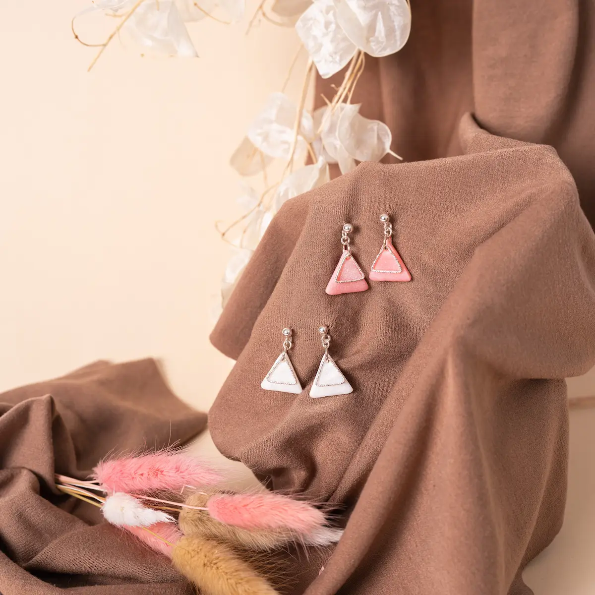 Pendiente de bolita de plata de ley 925 con arcilla polimérica un triángulo de color nácar rosa o nácar blanco, puedes elegir el que más te guste, y sobre él otro triángulo de plata de ley 925 martilleada. Un diseño elegante y exclusivo. Foto en modelo.