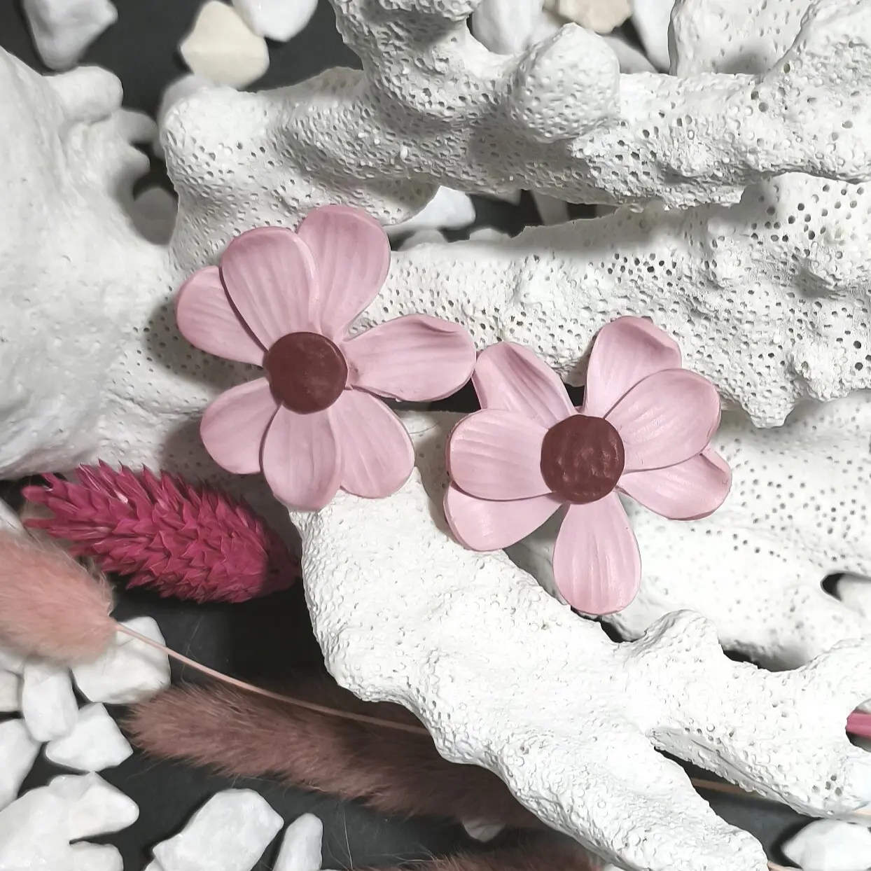 Pendientes artesanales de plata de ley 925 y arcilla polimérica en forma de flor rosa pegados al lóbulo.
