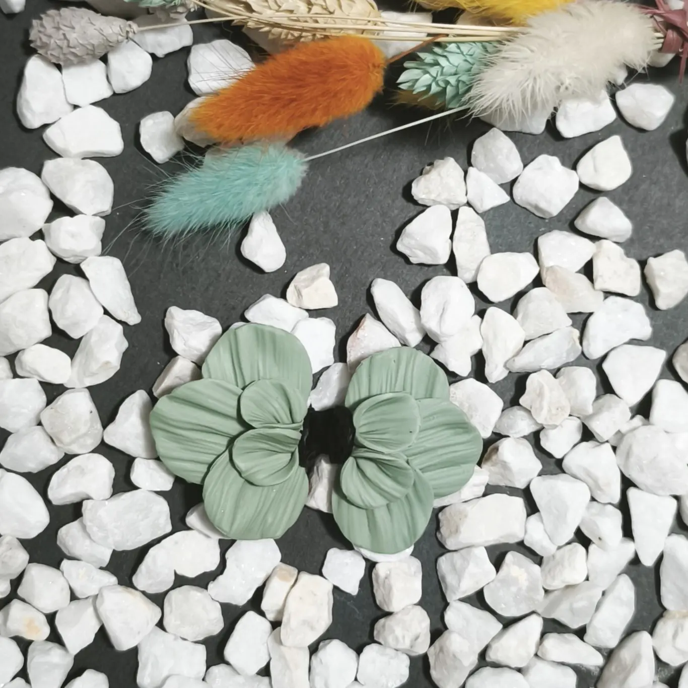 Pendientes artesanales de plata y arcilla polimérica en color verde menta con el centro negro en forma de media flor, un diseño elegante que aporta luminosidad.