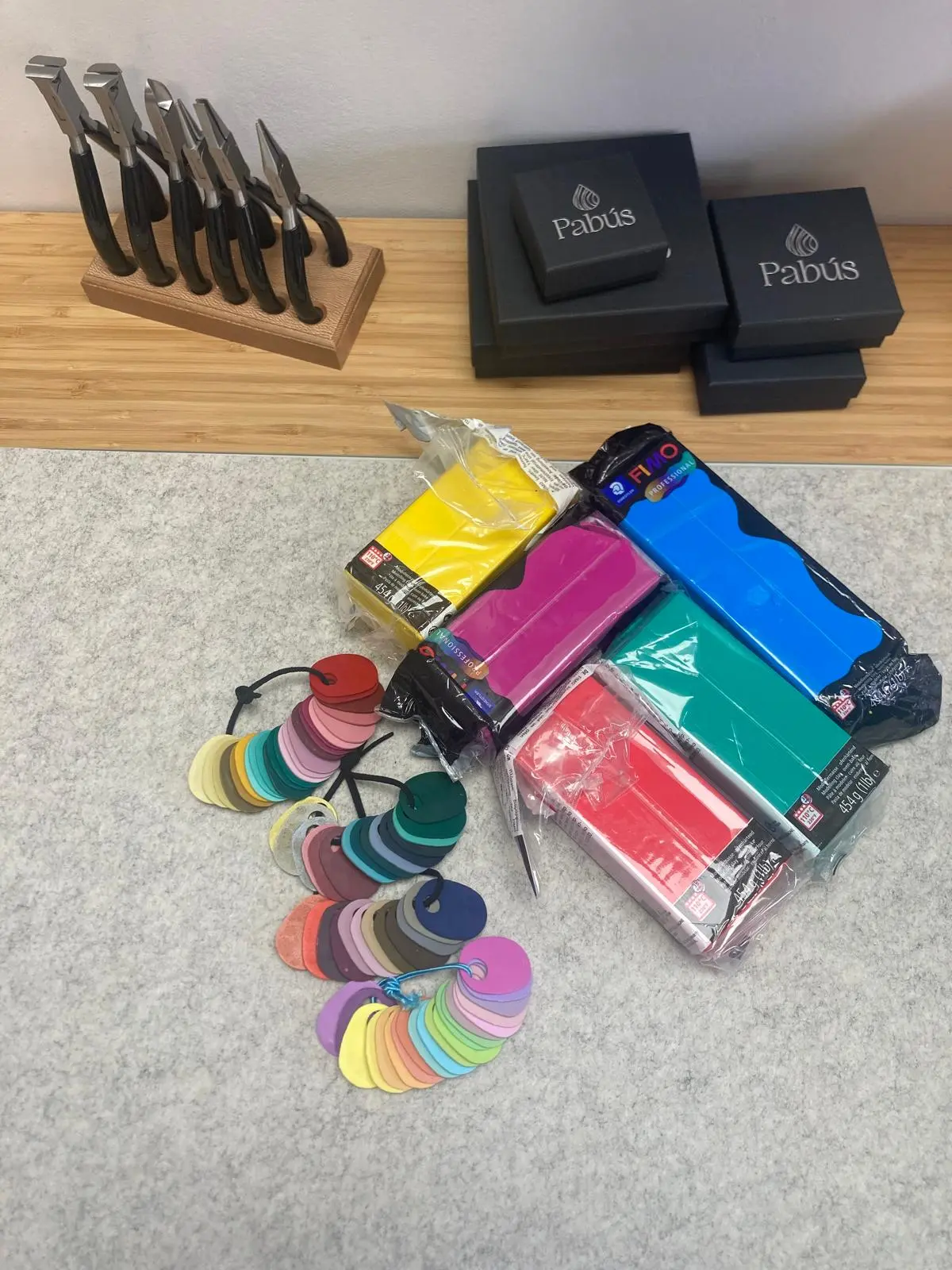 Mesa de trabajo de Pabús Bijoux con herramientas de joyería, muestrario de colores y arcilla polimérica para pendientes artesanales en Bilbao.